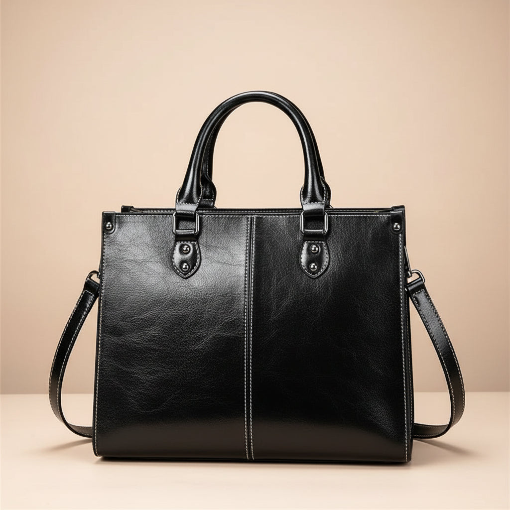 Black leather handbag with shoulder strap on a white background