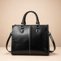 Black leather handbag with shoulder strap on a white background